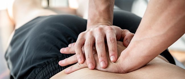 A photo of two hands on a back showing a person performing a physical adjustment.