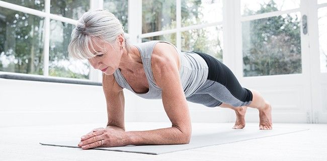 An Older Woman is Doing a Plank on a Yoga Mat — Mark O'Brien Chiropractic in West End, QLD