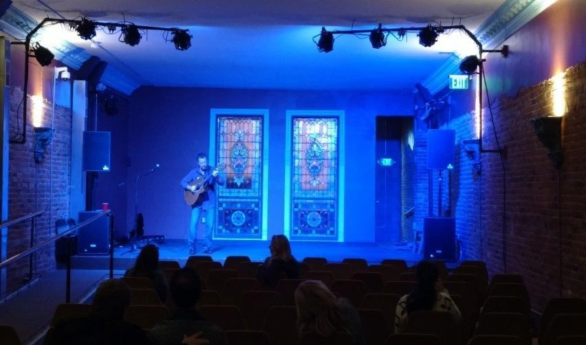 A man playing a guitar on a stage with blue lights