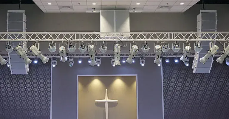 There is a cross in the middle of the stage in a church.