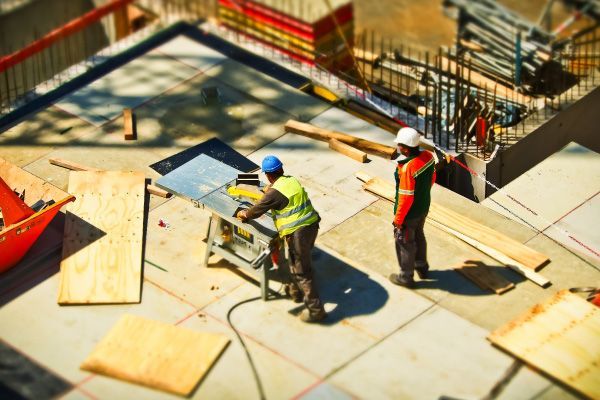 Construction workers installing panels on a rooftop with safety gear and scaffolding.