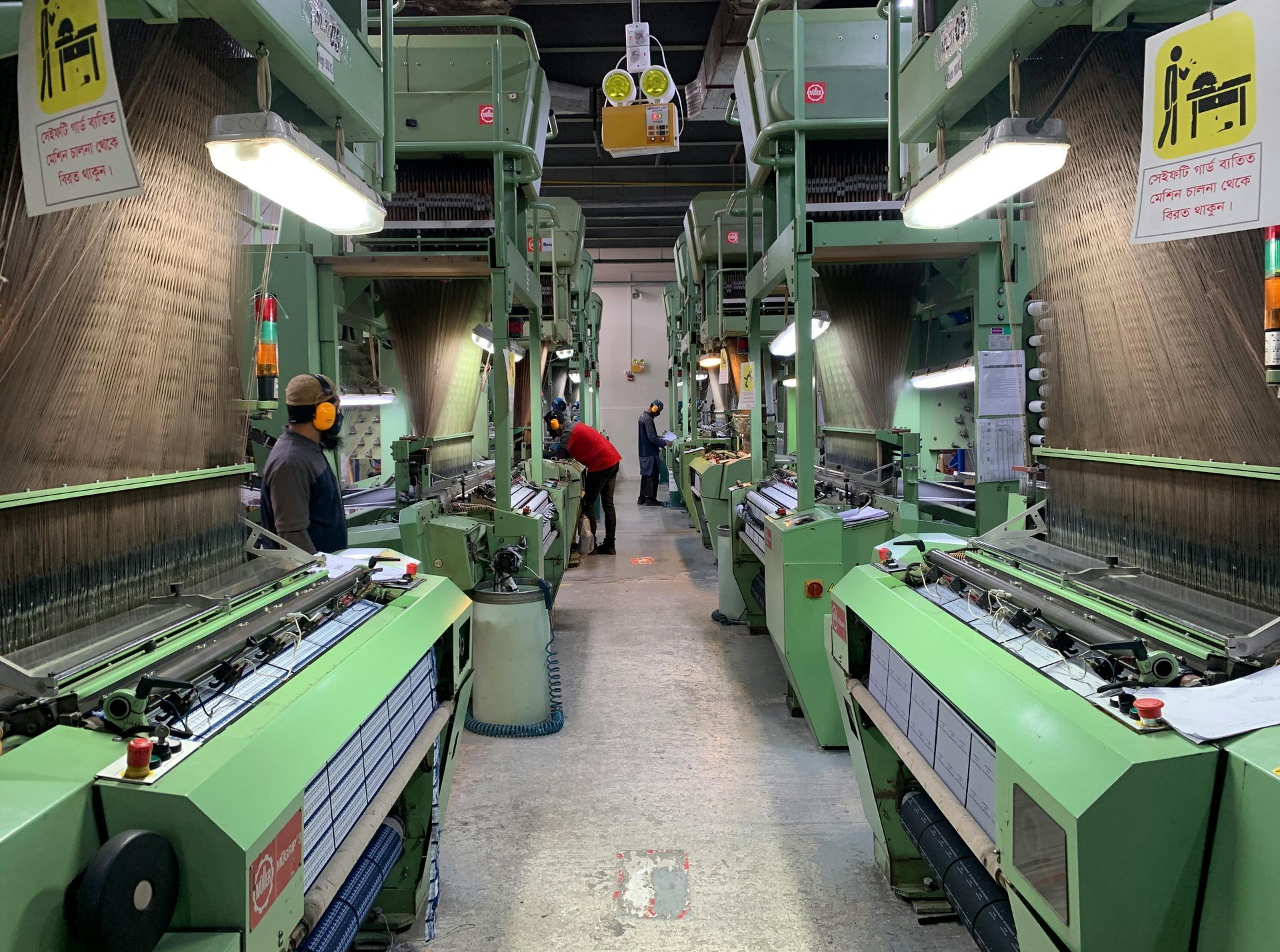 Two workers reviewing paperwork beside industrial machinery in a factory.