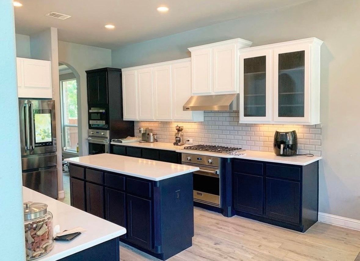A kitchen with white cabinets , stainless steel appliances , and a large island.