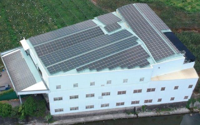 從高處俯瞰，可以看到屋頂裝有太陽能板、周圍綠樹環繞的建築物。