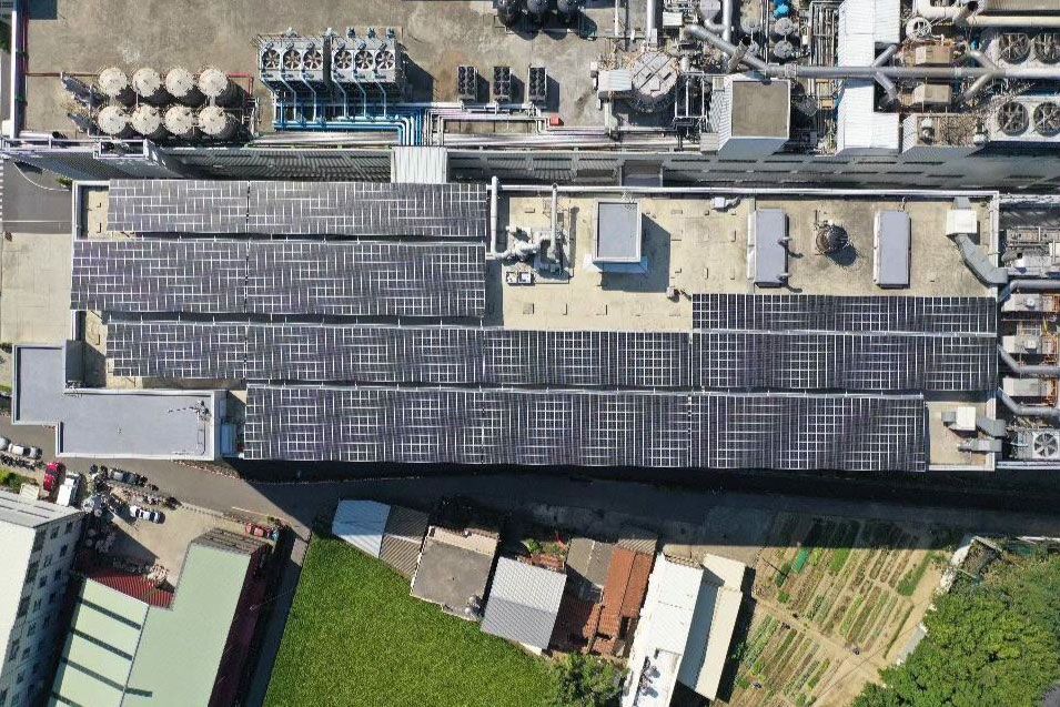 從空中俯瞰，可以看到一棟建築物的屋頂上覆蓋著太陽能電池板和工業設備。