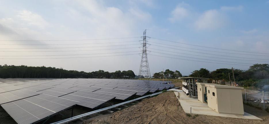 田野裡的太陽能板，遠處是輸電塔和公用設施建築，天空陰雲密布。
