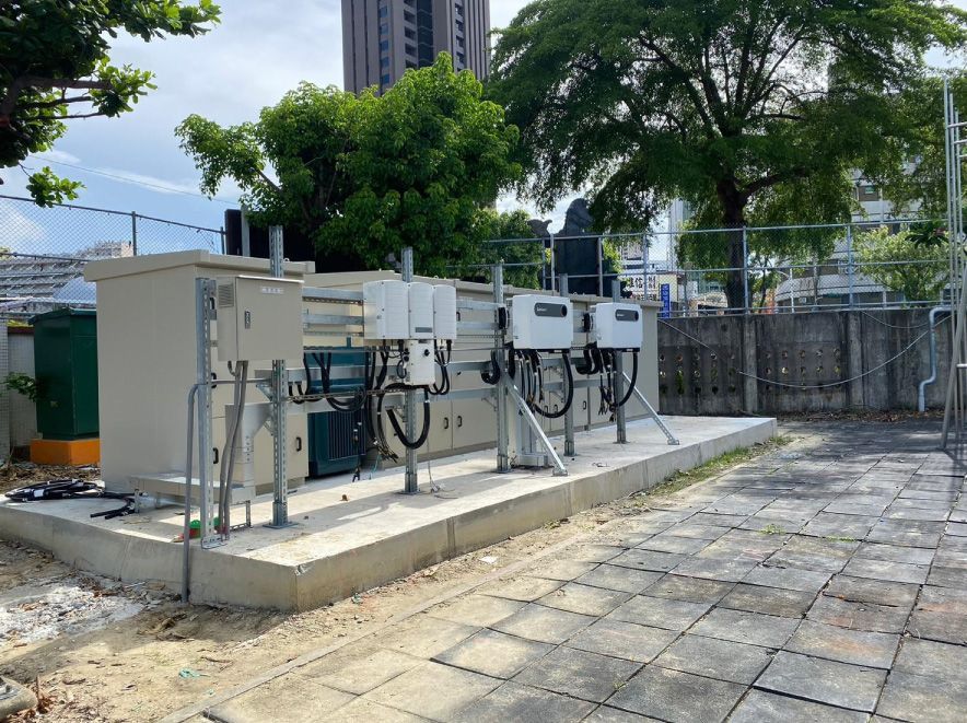 戶外電氣設備安裝在混凝土基座上，背景有樹木和建築物。