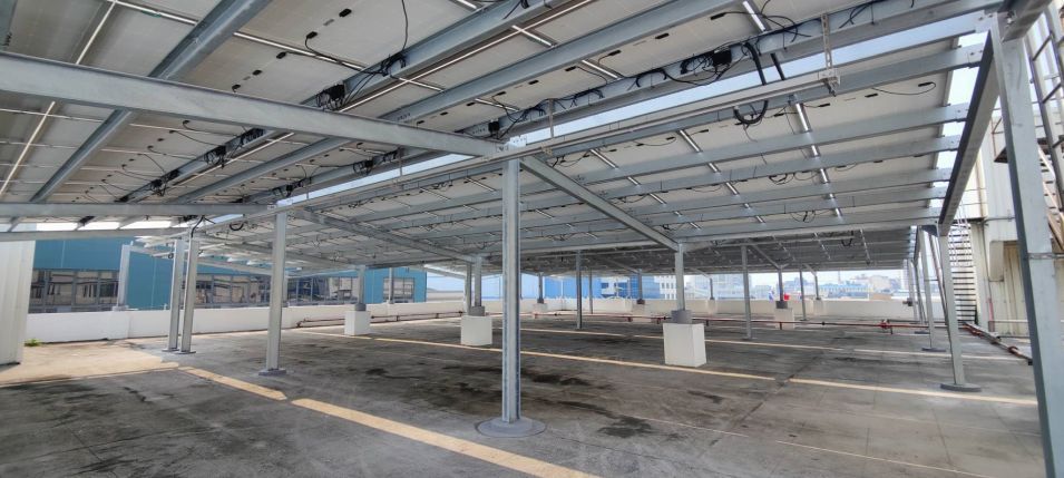 金屬結構下的太陽能板。背景是藍色建築。建築工地。