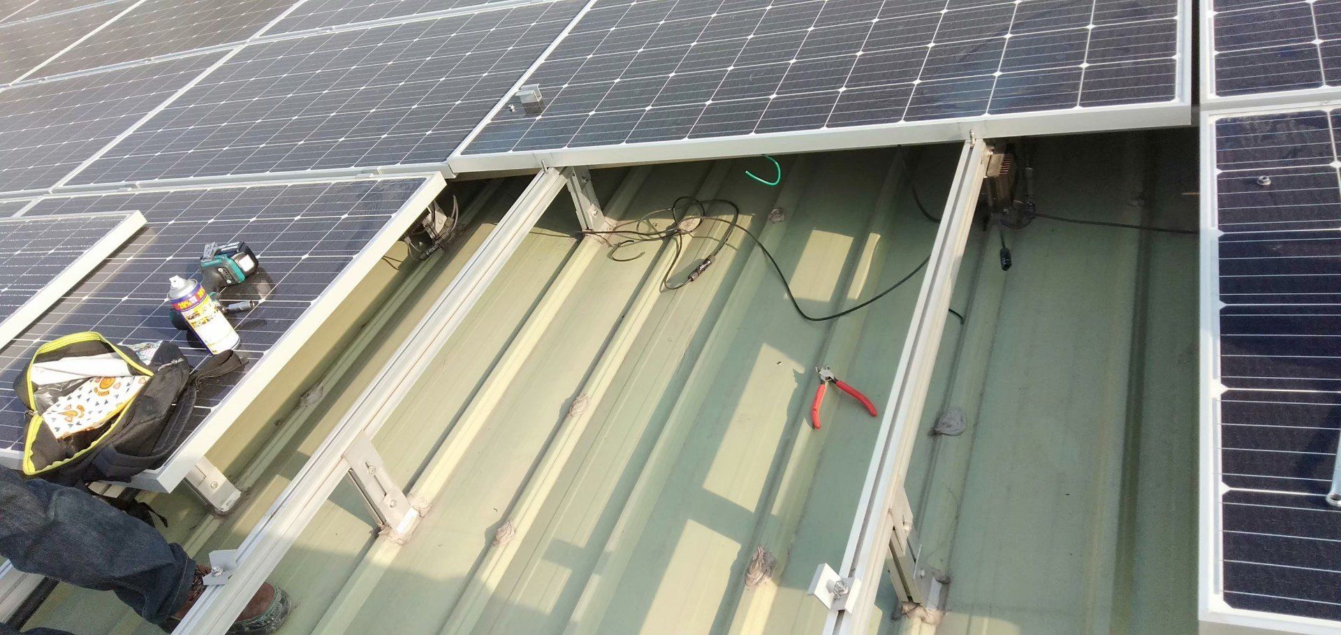 有人在屋頂上安裝太陽能板，可以看到工具、電線和金屬框架。