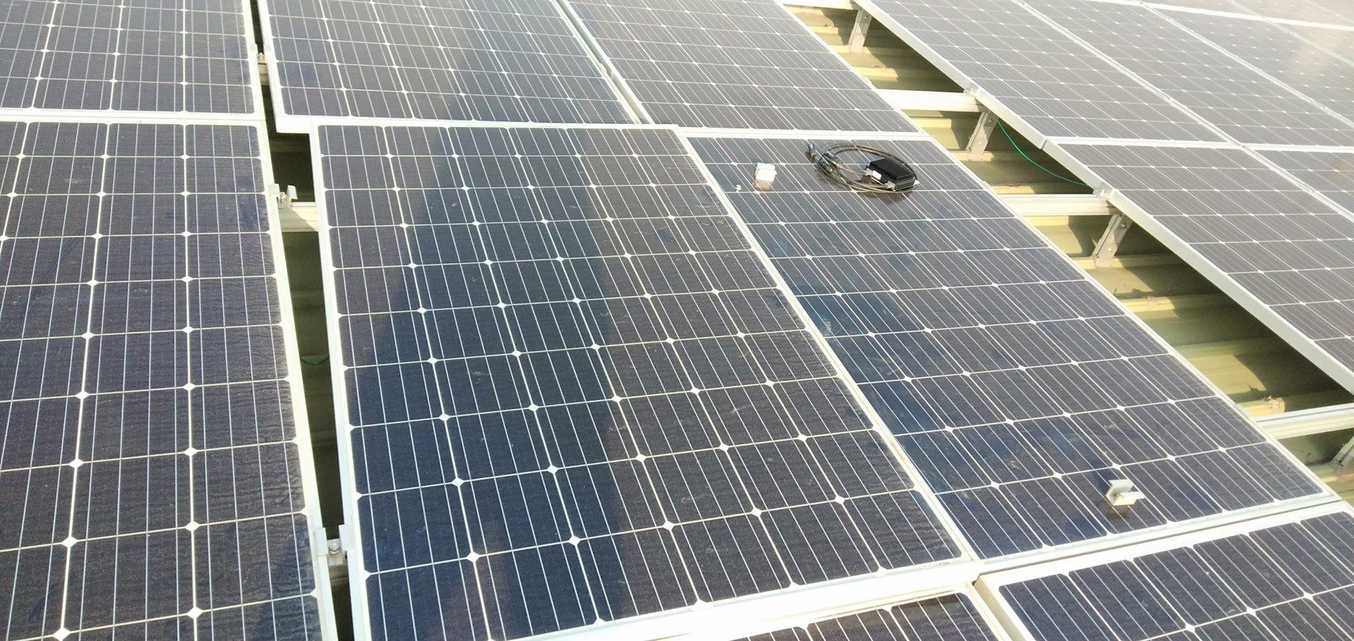 屋頂上的太陽能電池板。電池板上放著一個黑色設備，可能是用於維護或清潔。