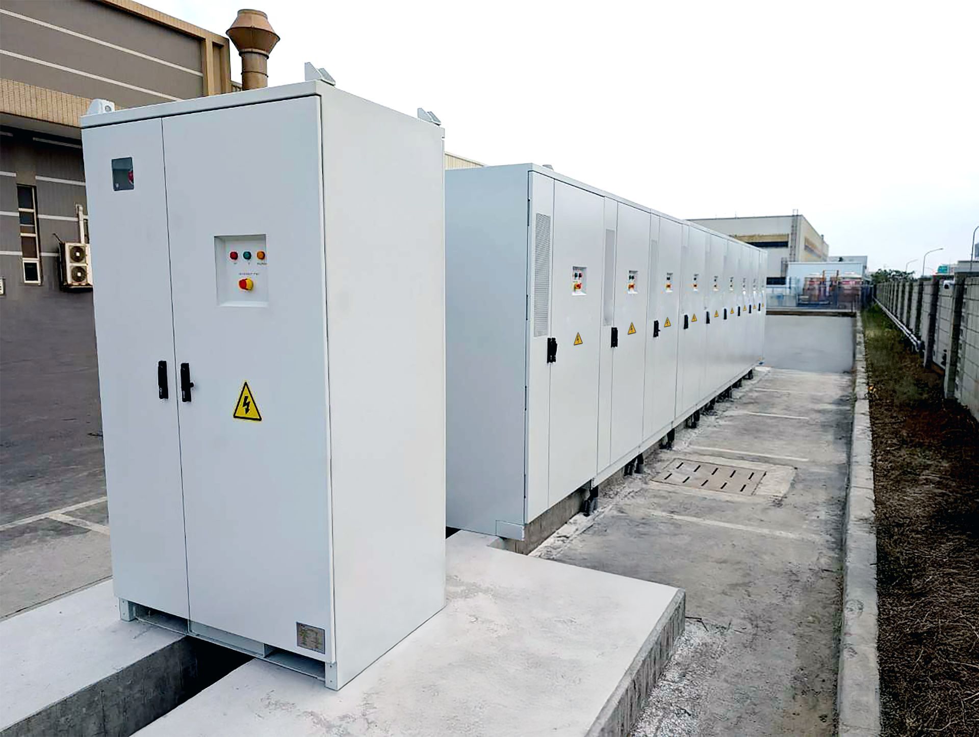 建築物附近，室外擺放著一排排大型白色配電櫃，很可能是用於電力分配的。