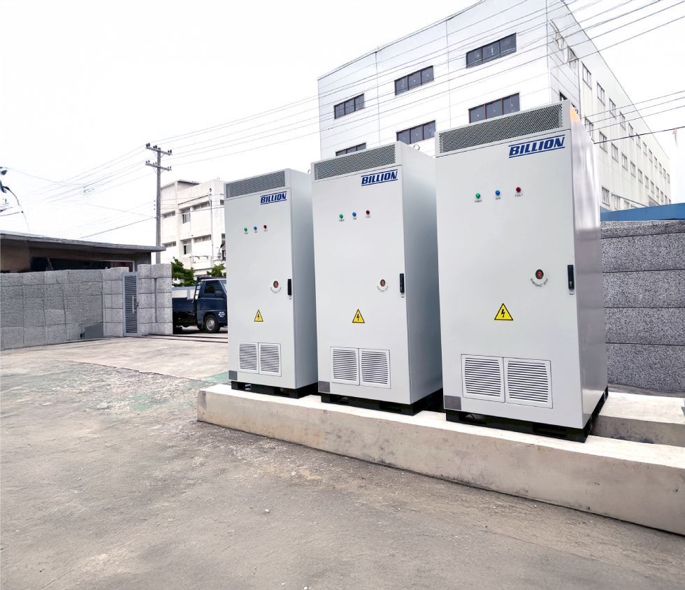 戶外三個有警示標誌的白色配電櫃。背景是建築物和電線桿。
