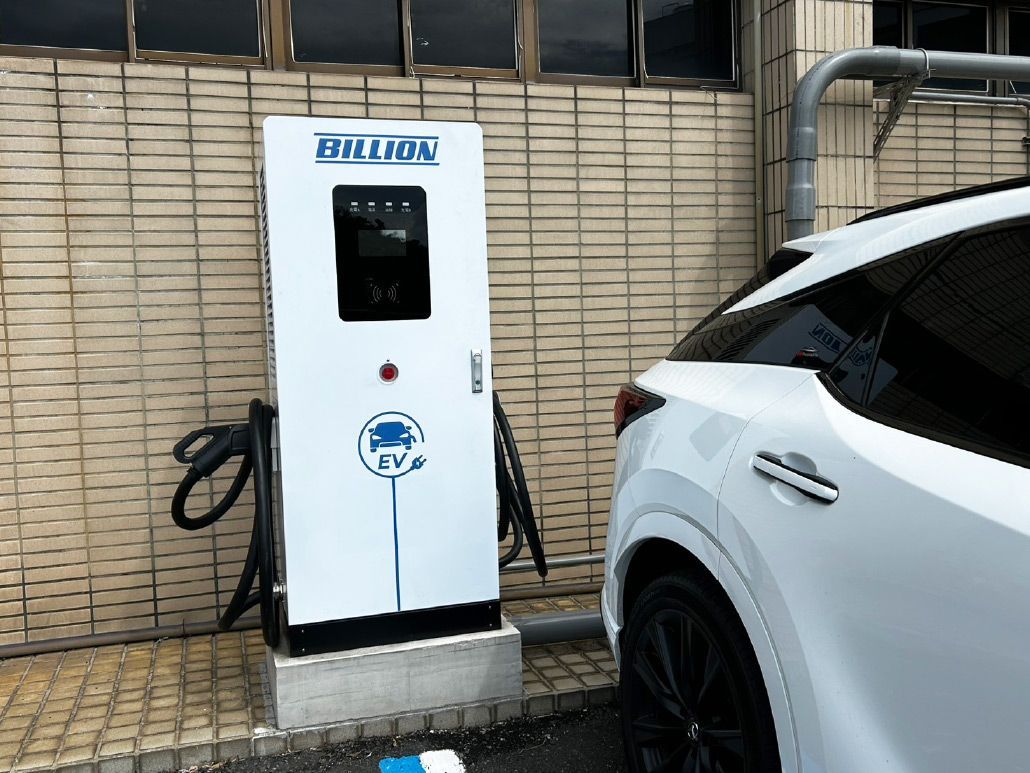 白色電動車正在靠磚牆的白色充電站充電。