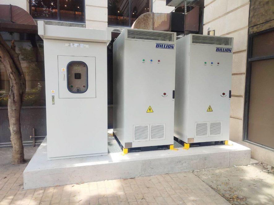 建築物外水泥地上放著三個白色配電櫃。