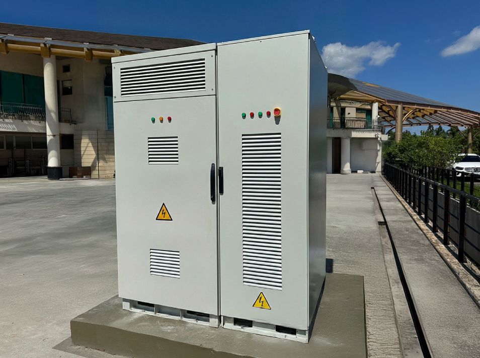 灰色電氣櫃，帶有通風格柵和警告標誌，位於建築物前的室外。