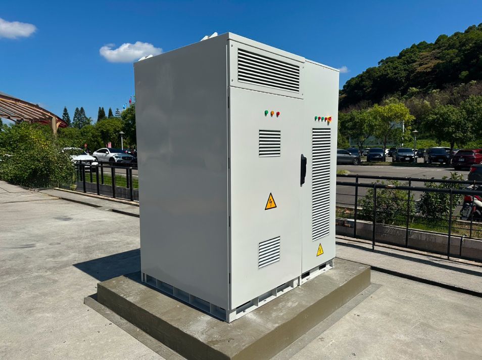 戶外混凝土底座上的大型灰色配電箱，帶有通風條和安全標誌。