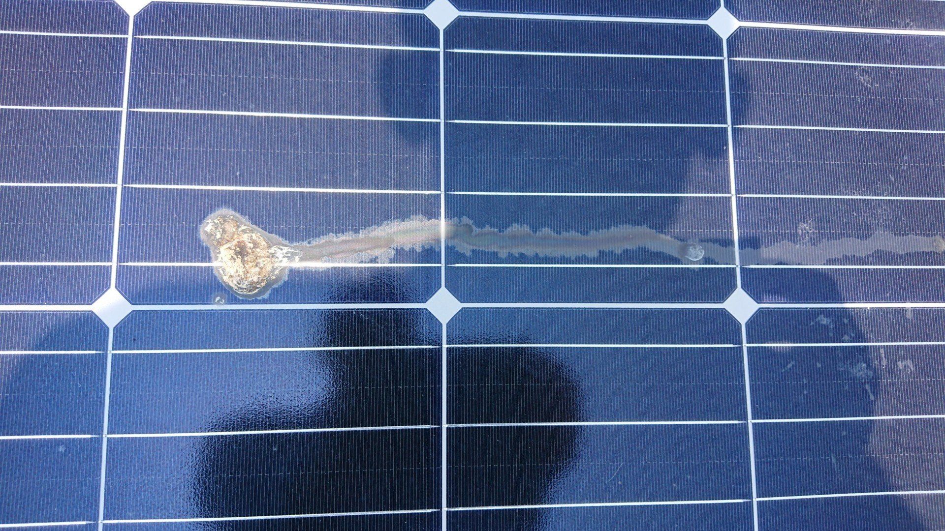 損壞的太陽能電池板，有裂縫和變色區域。藍色電池片周圍有銀色導線勾勒輪廓。