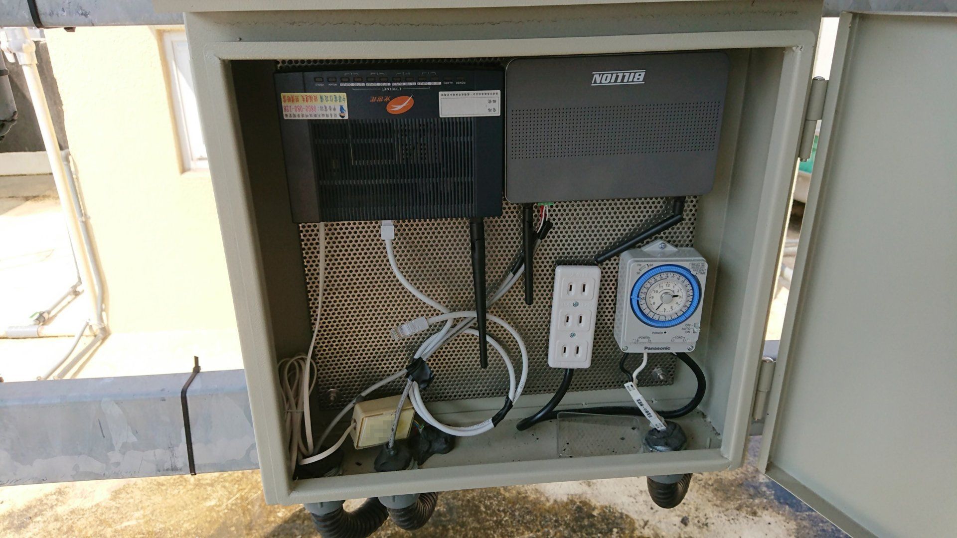 屋頂上的金屬箱內裝有電子元件，包括定時器、插座和網路設備。
