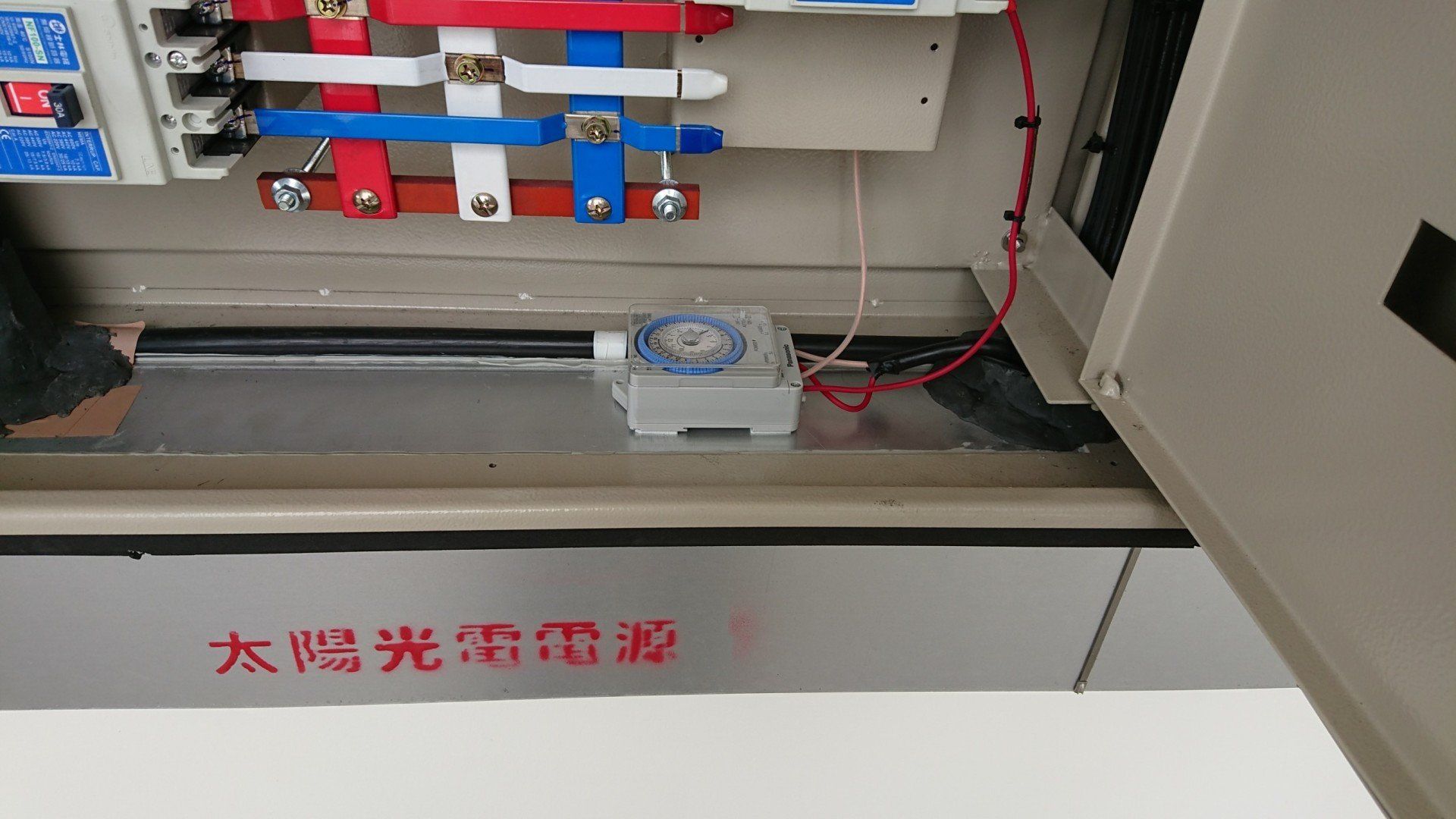 配有定時器、電線和斷路器的配電箱。灰色金屬盒，上面有中文文字。