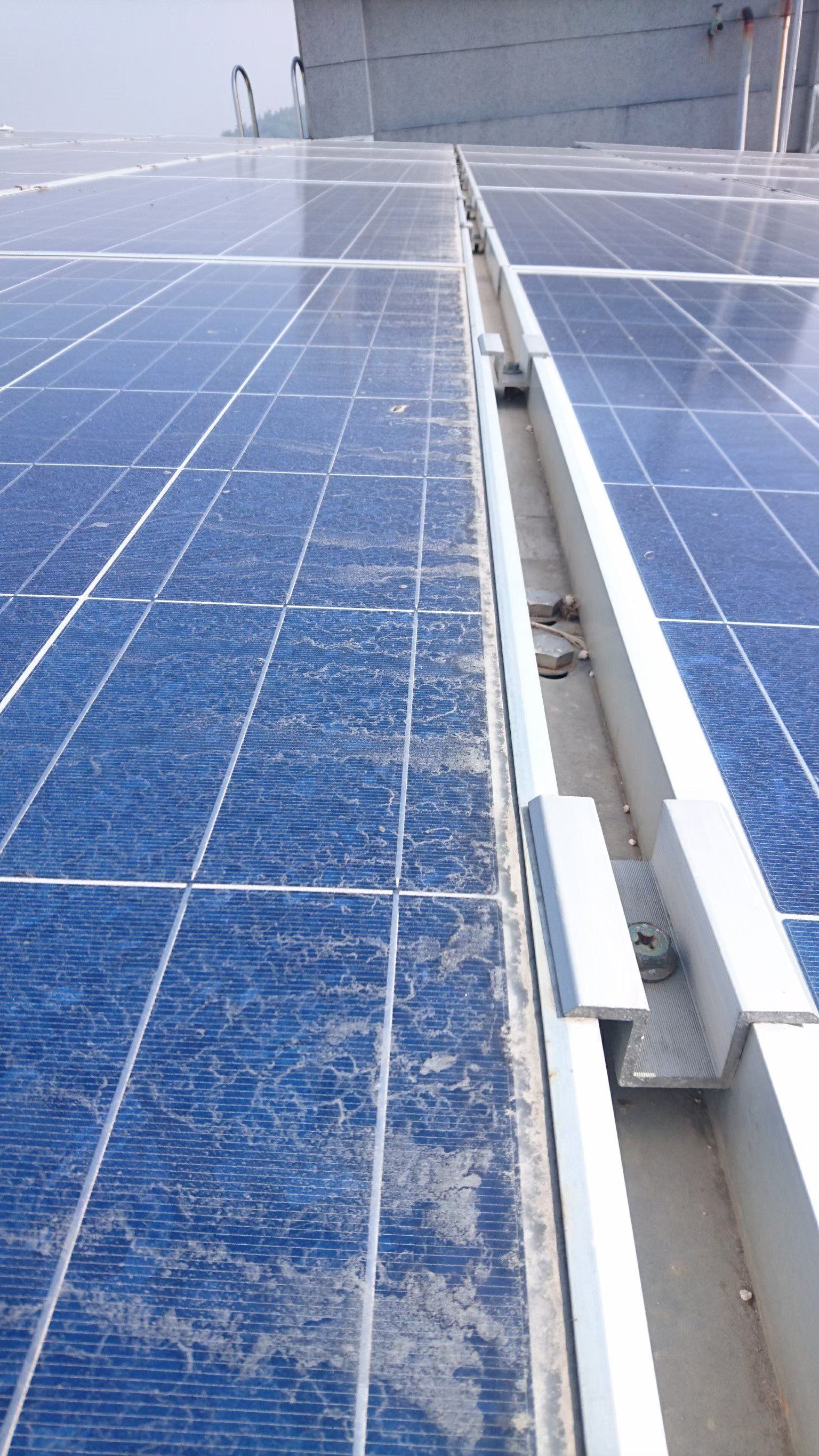 屋頂上的太陽能電池板，配有銀色軌道系統，表面積滿了灰塵。
