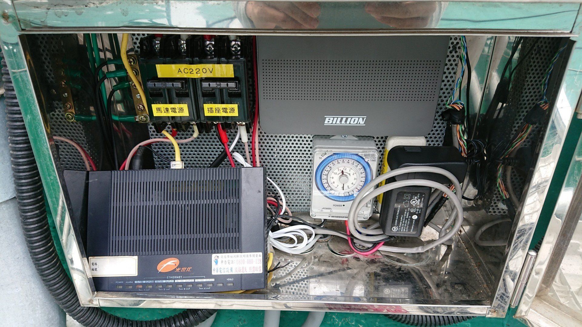 金屬櫃內裝有電氣元件：斷路器、定時器、電線和黑盒子設備。