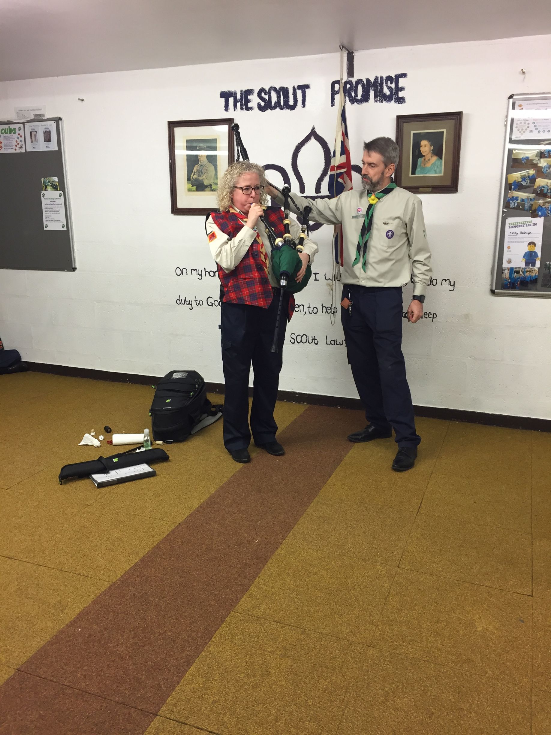 Two people are standing in a room with a sign that says the scout promise
