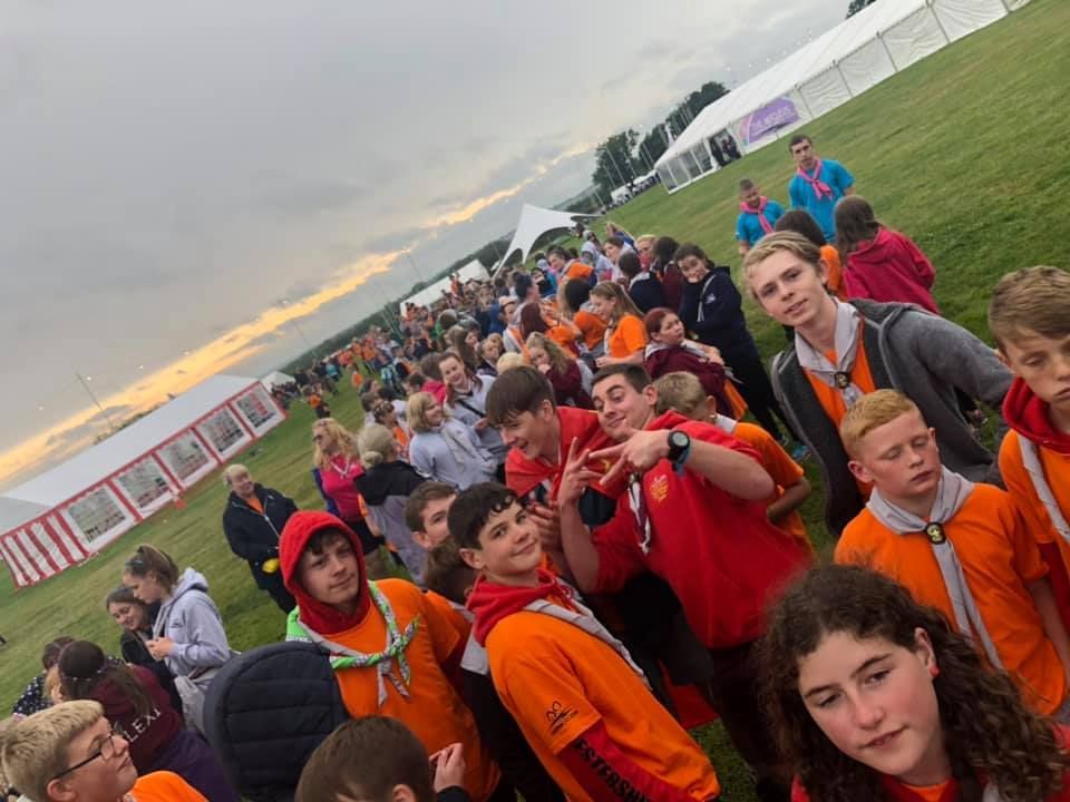 A group of people are standing in a field in front of a tent.