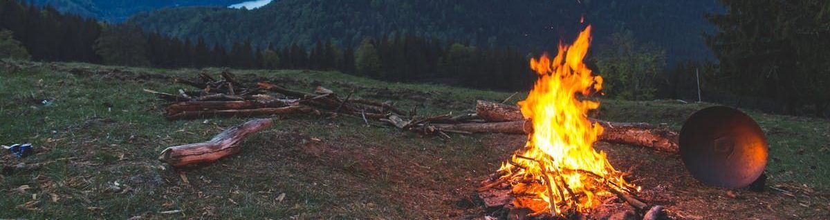 A campfire is sitting in the middle of a grassy field at night.