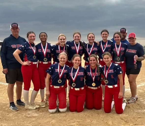 Softball team in bright pink jerseys posing on a field after a game