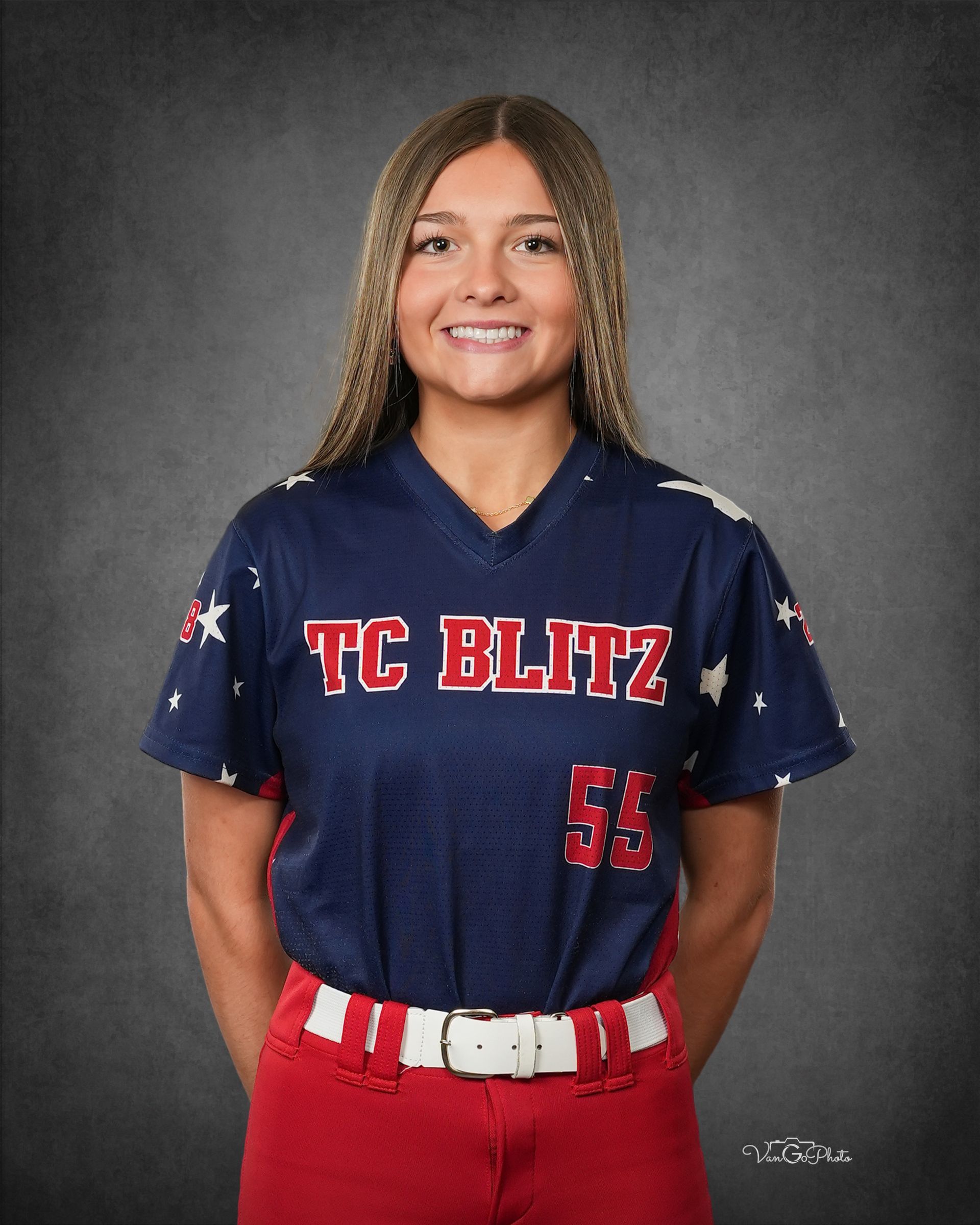 Portrait of a softball player in a navy and red TC BLITZ uniform against a gray backdrop