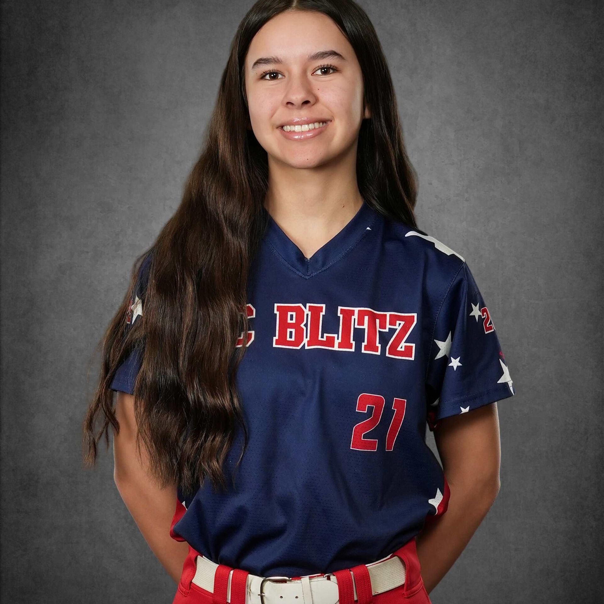 Portrait of a smiling softball player in a navy blue jersey with “BLITZ” and number 21