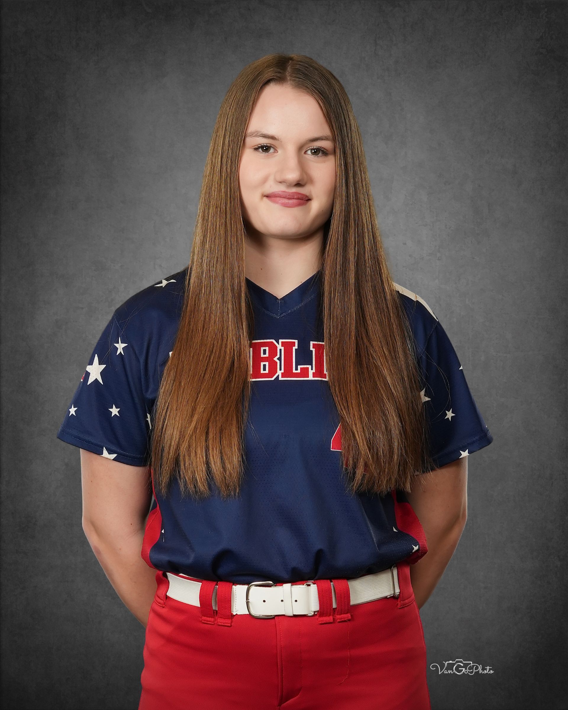 Person in a navy and red sports uniform standing against a gray backdrop, facing forward with a slight smile.