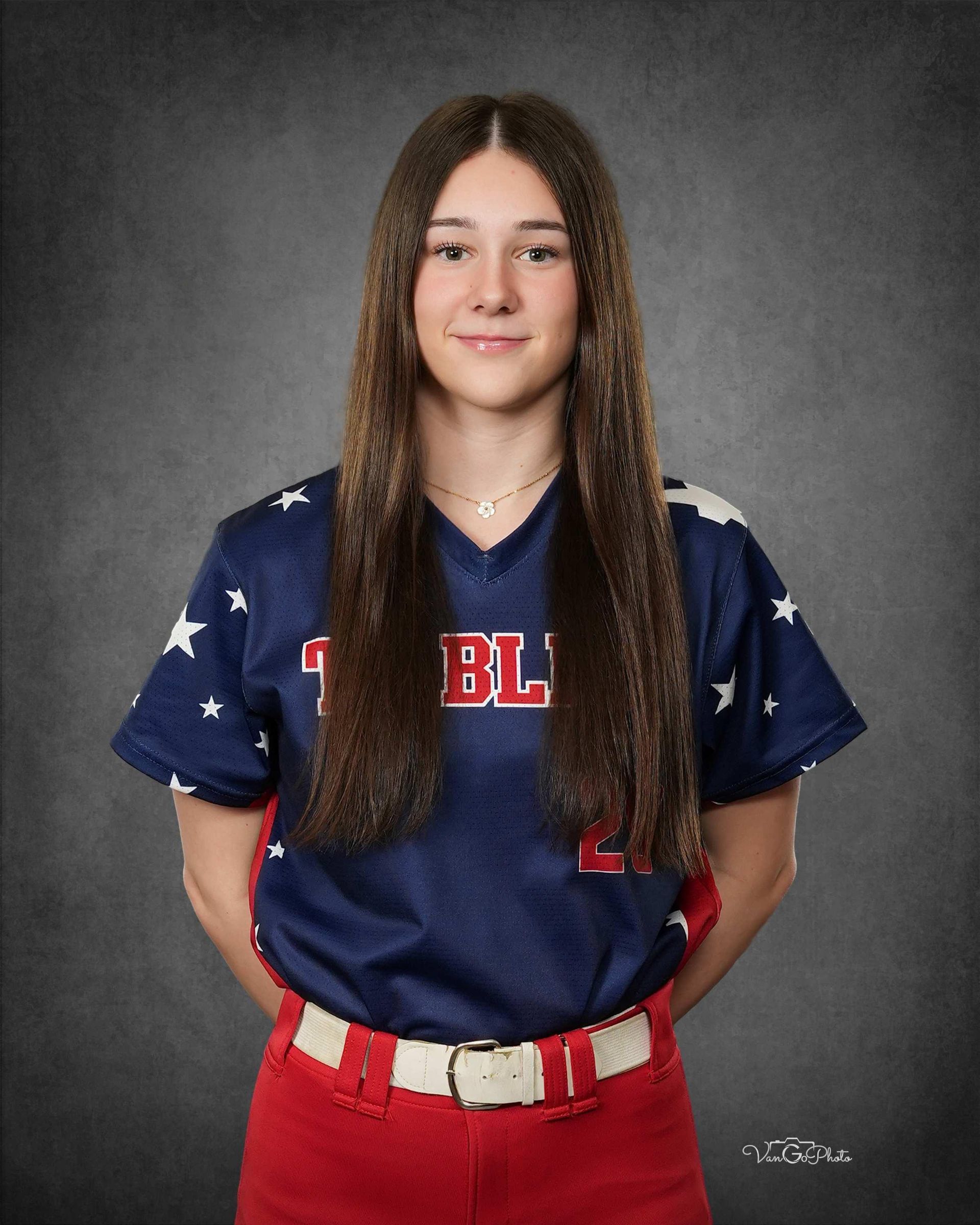 Studio portrait of a person in a navy and red sports uniform against a gray backdrop