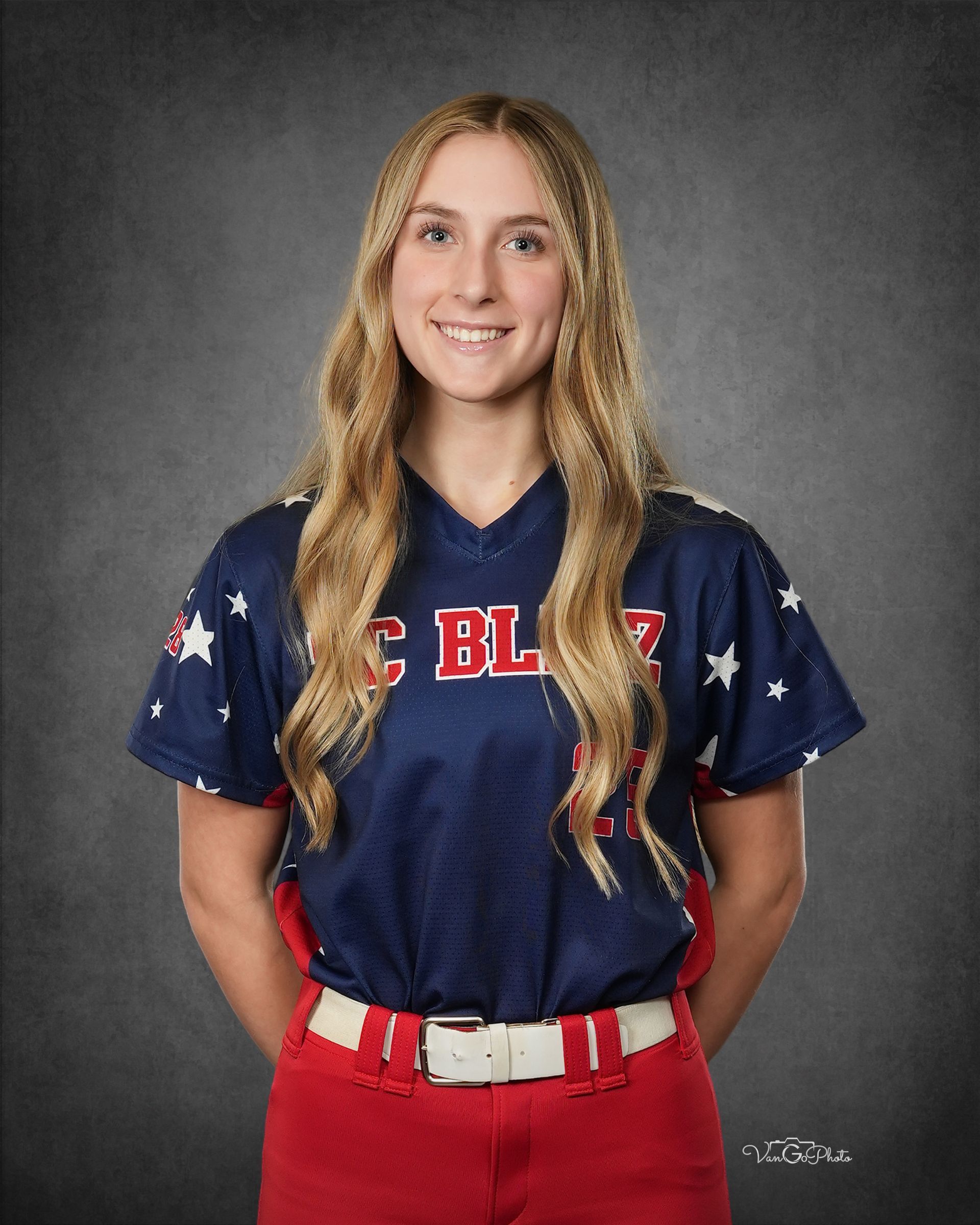 Portrait of a smiling athlete in a navy jersey and red pants against a gray studio backdrop.