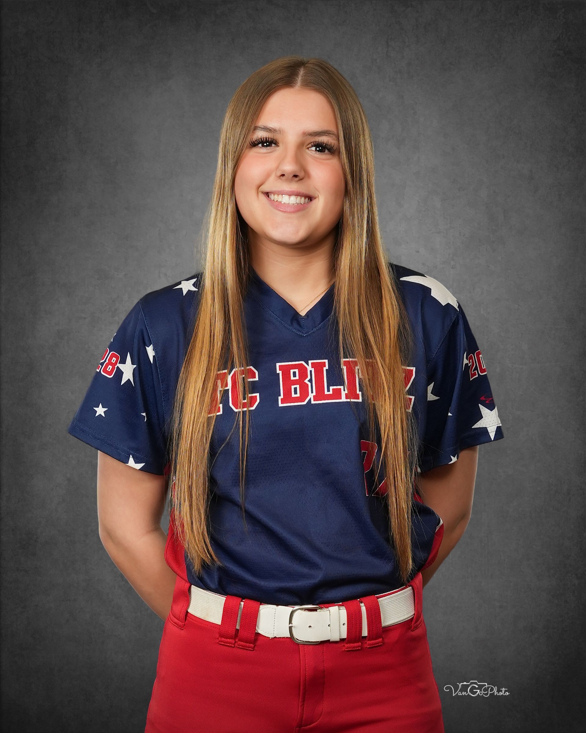 Portrait of a smiling athlete in a navy and red uniform against a gray studio backdrop