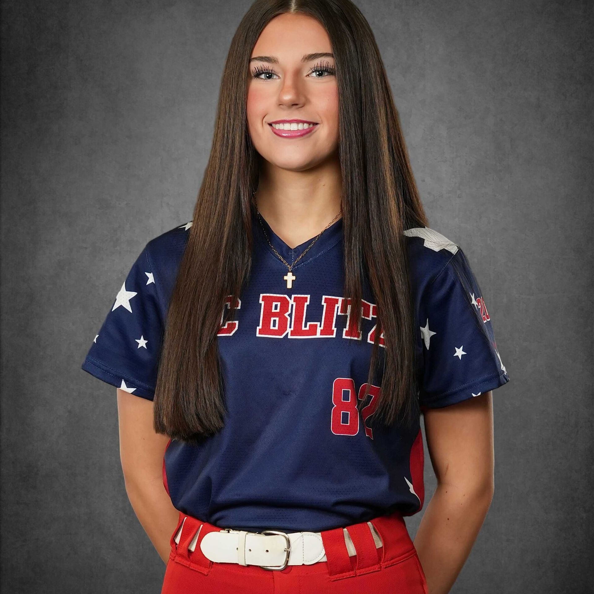 Portrait of a smiling athlete in a navy jersey and red pants against a gray studio backdrop