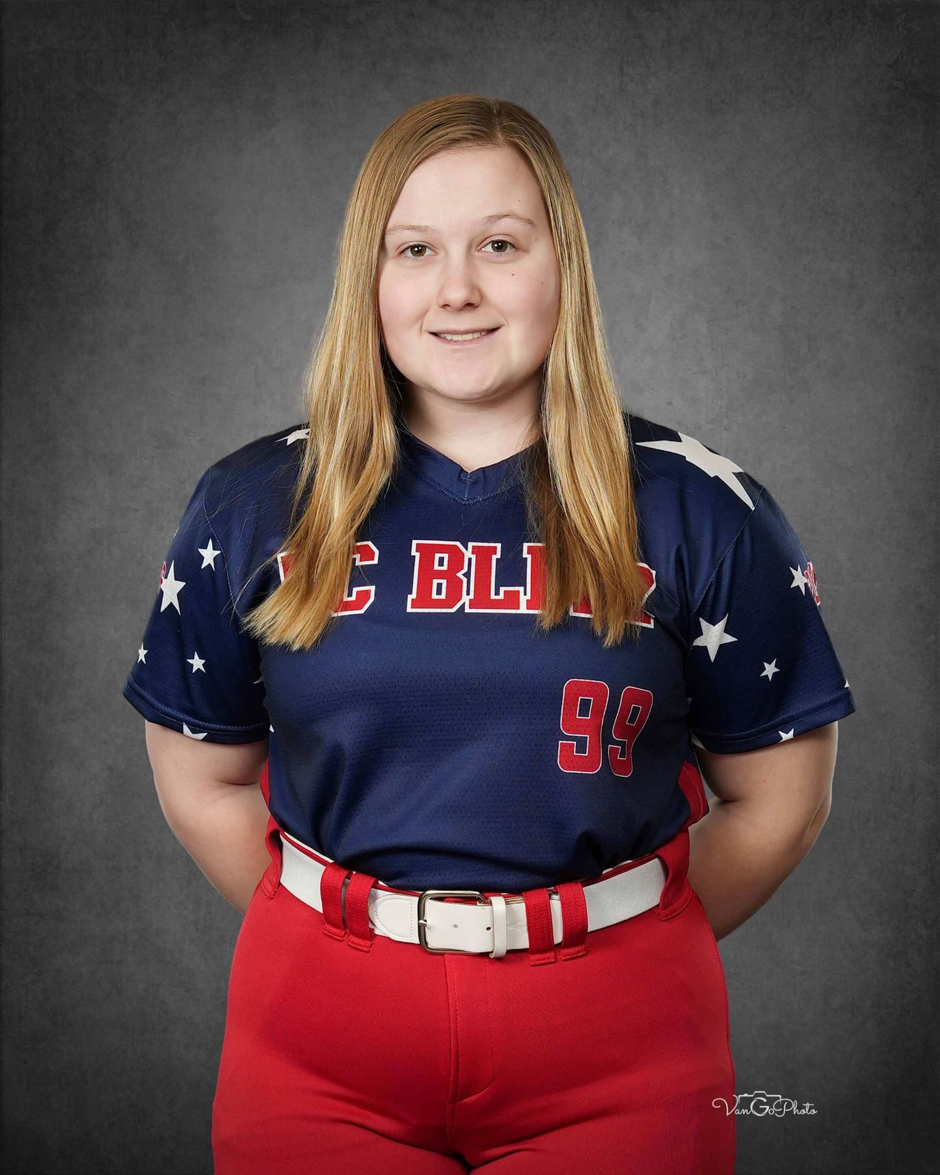 Woman in a navy and red sports uniform posing against a gray studio backdrop.