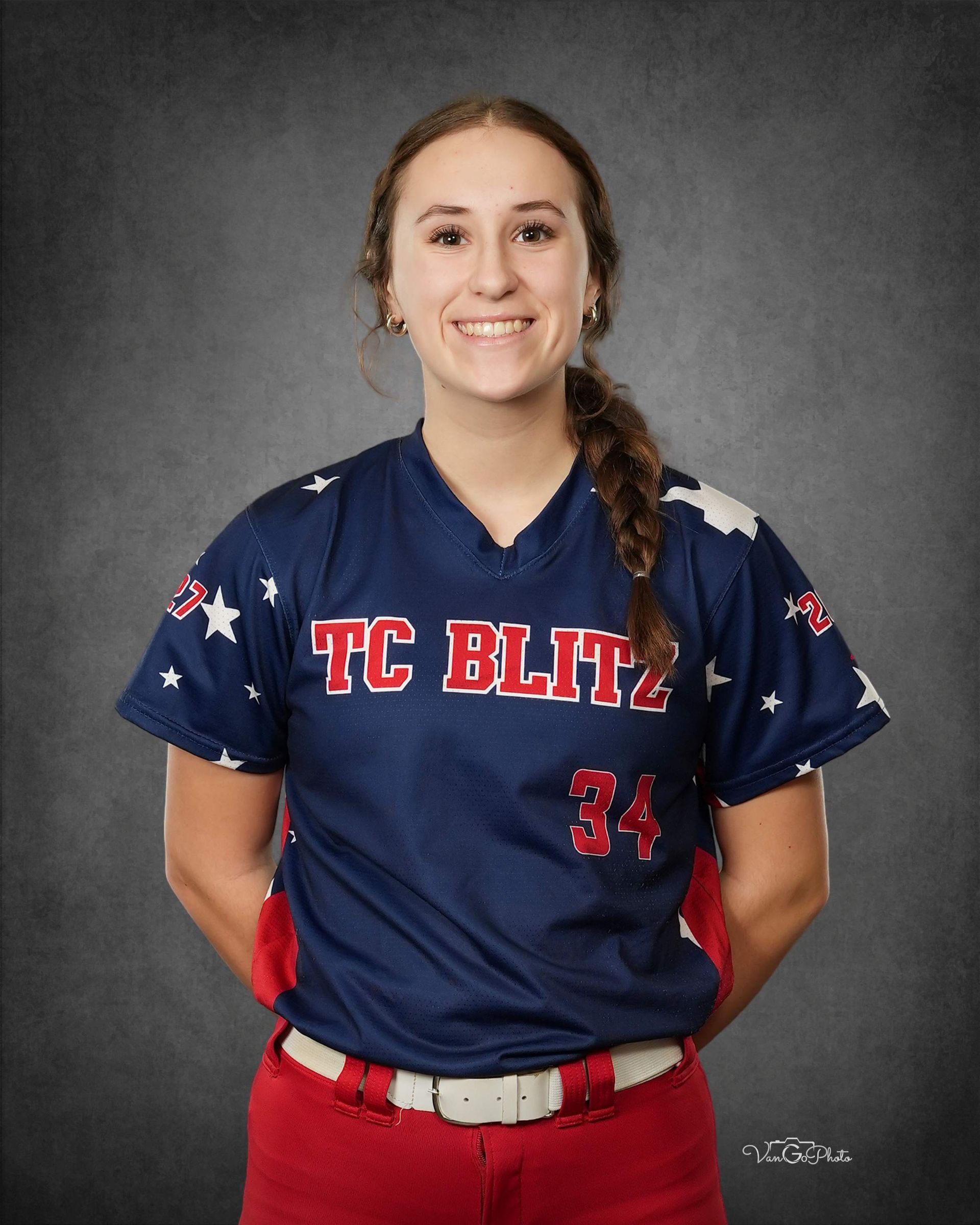 Portrait of a smiling softball player in a navy TC Blitz jersey with red pants and a braid.