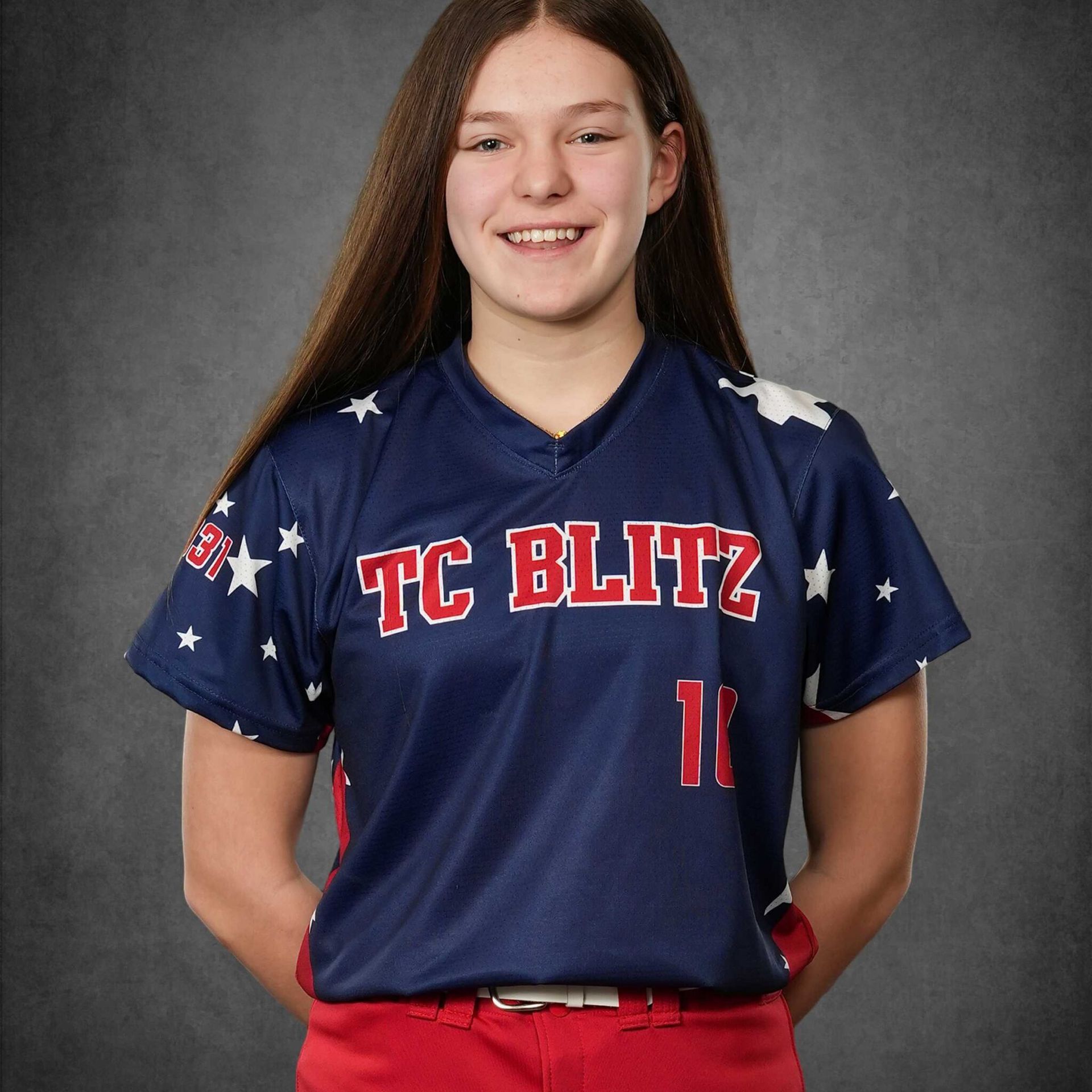 Portrait of a smiling softball player in a navy TC Blitz jersey on a gray backdrop