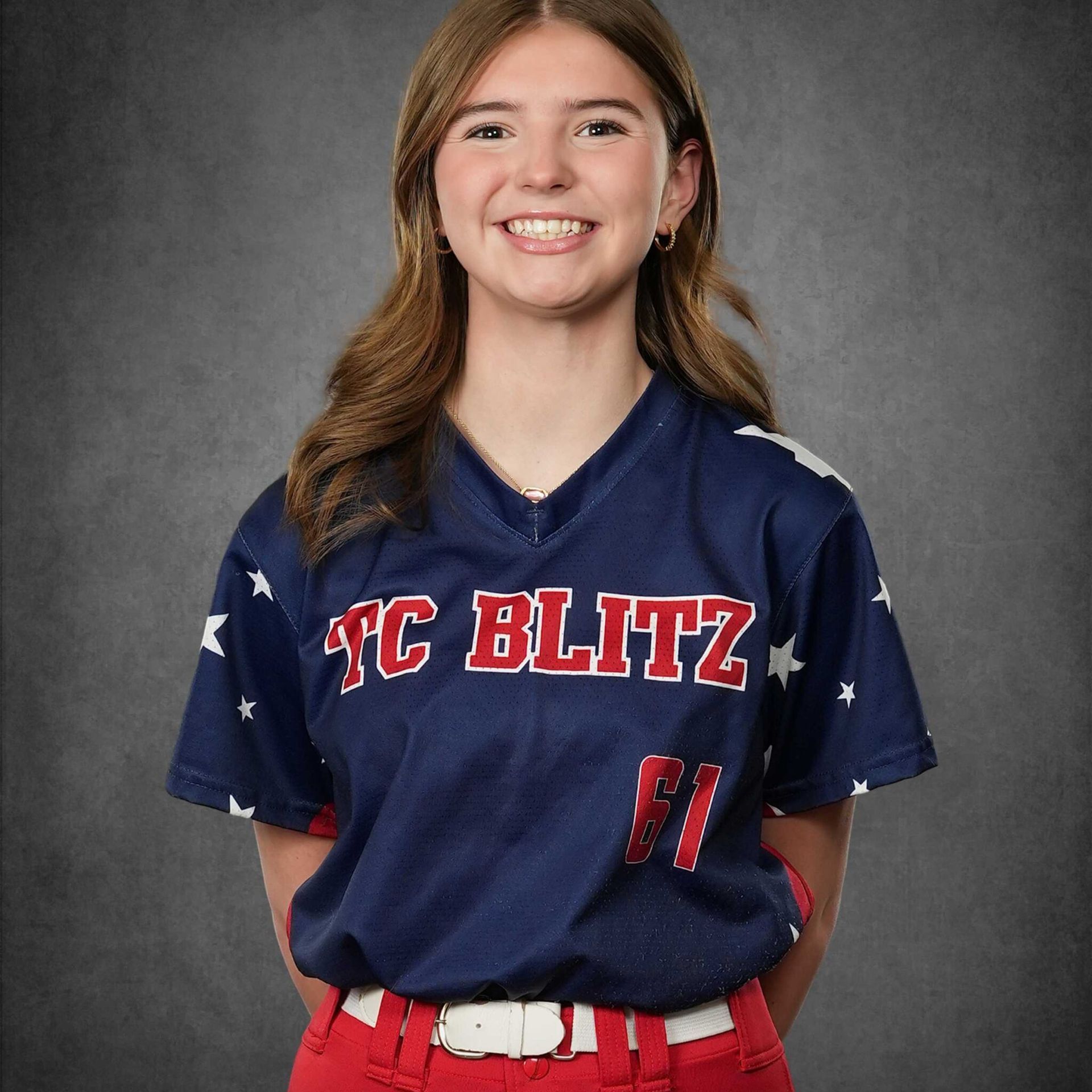 Smiling person in navy and red sports uniform against a gray studio backdrop