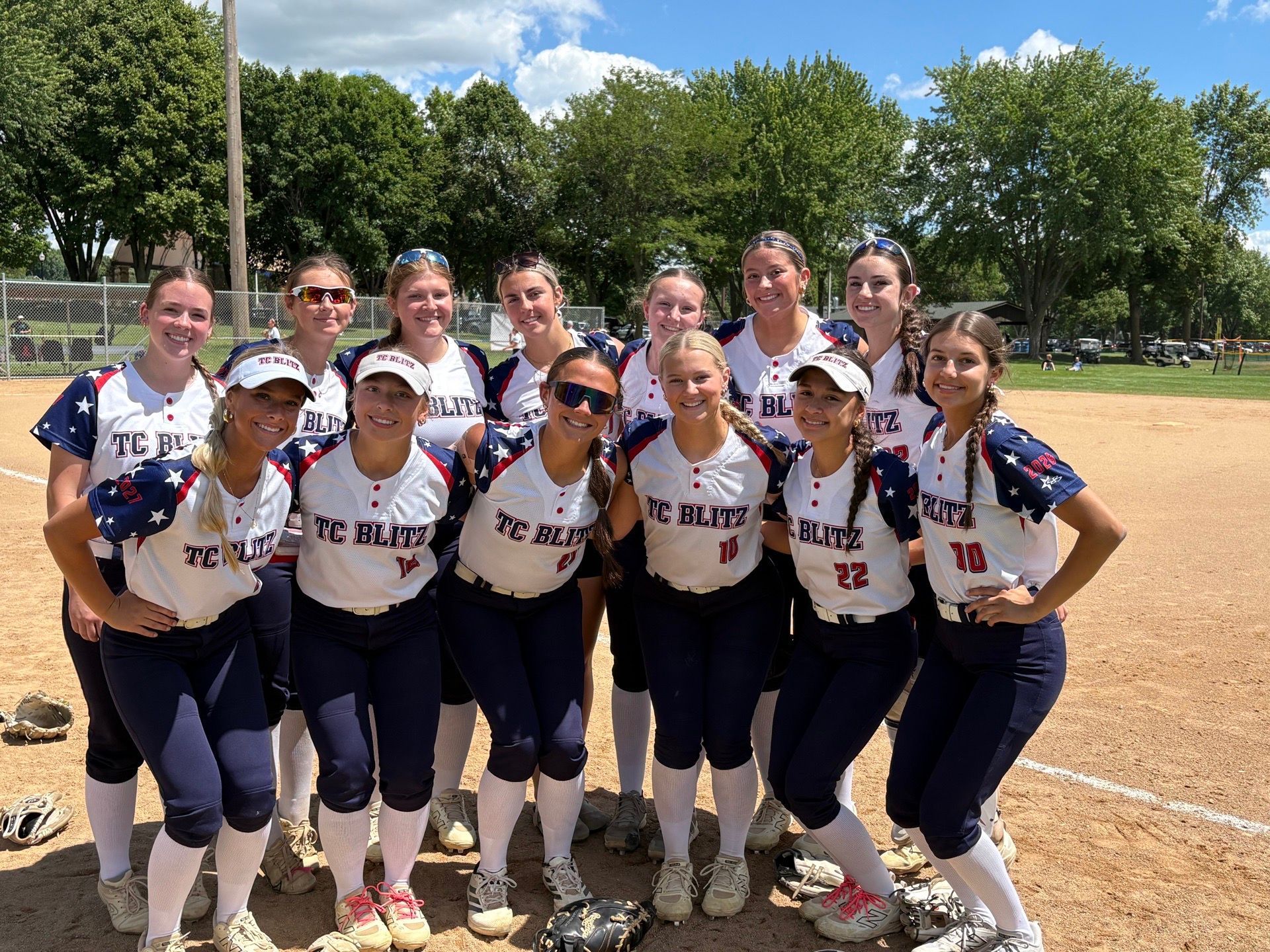 Softball team in bright pink jerseys posing on a field after a game