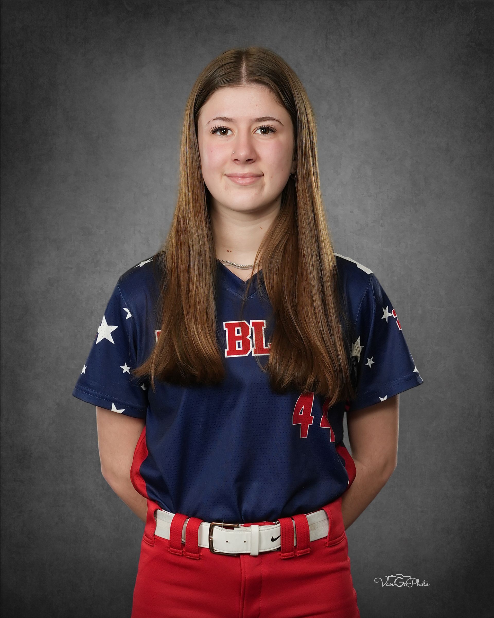 Portrait of a person in a navy jersey and red pants standing against a gray backdrop.