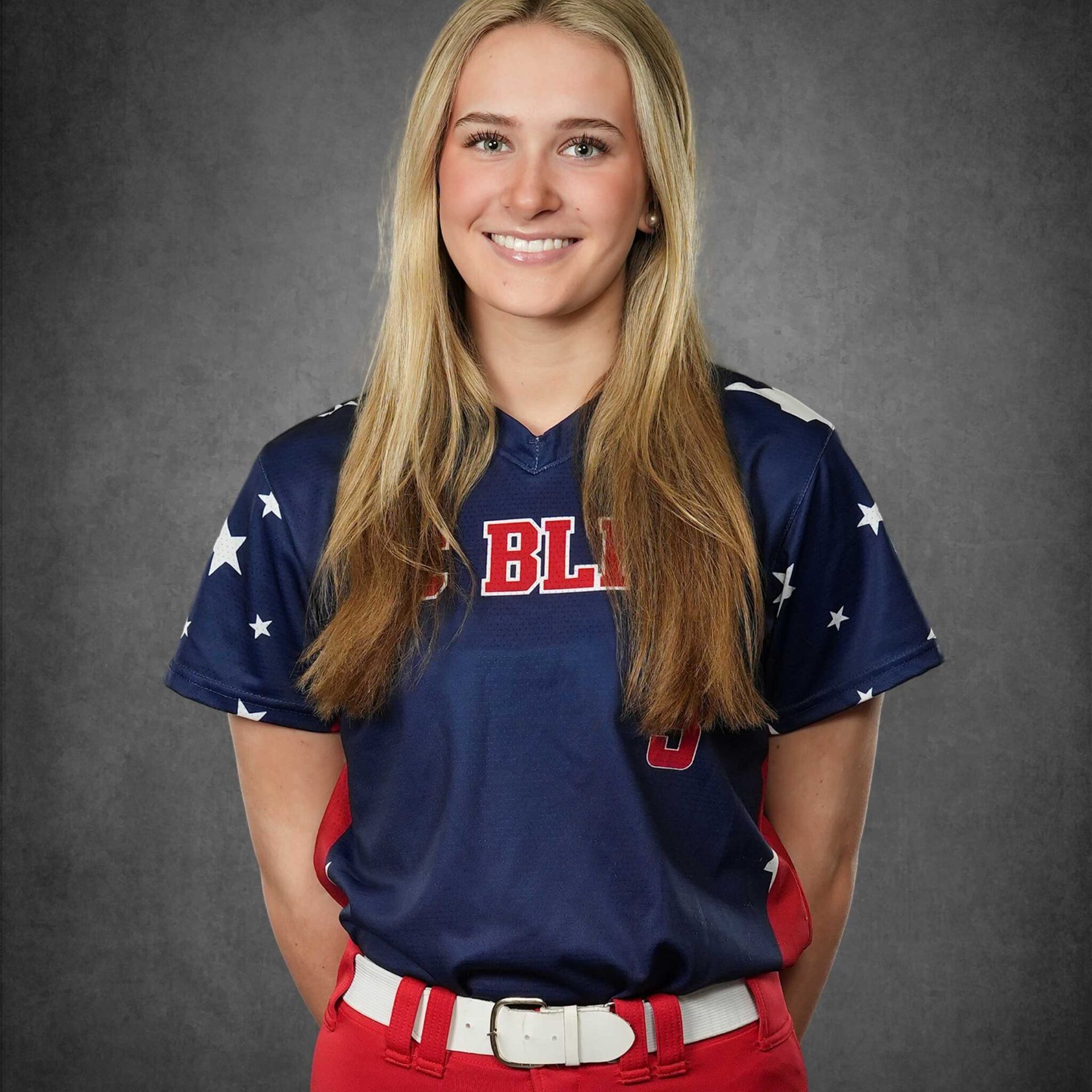 Smiling athlete in navy uniform with stars and red accents, posed against a gray studio backdrop.