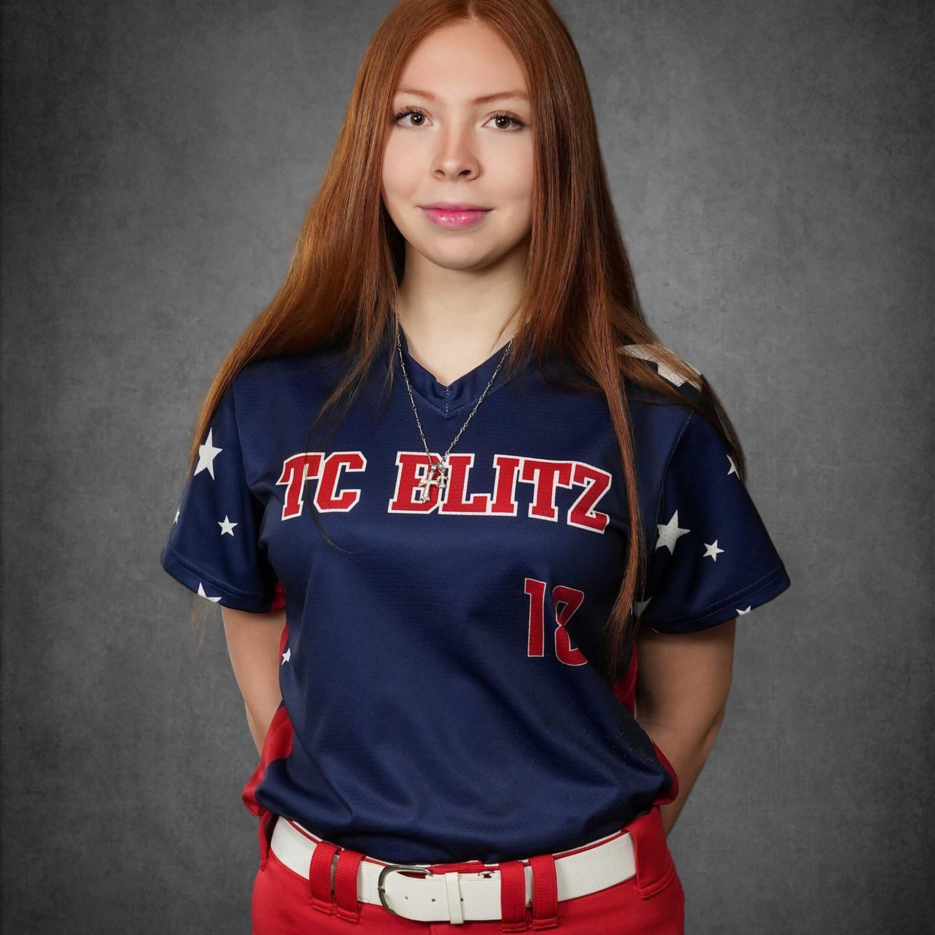 Portrait of a softball player in navy and red TC ELITZ uniform against a gray backdrop