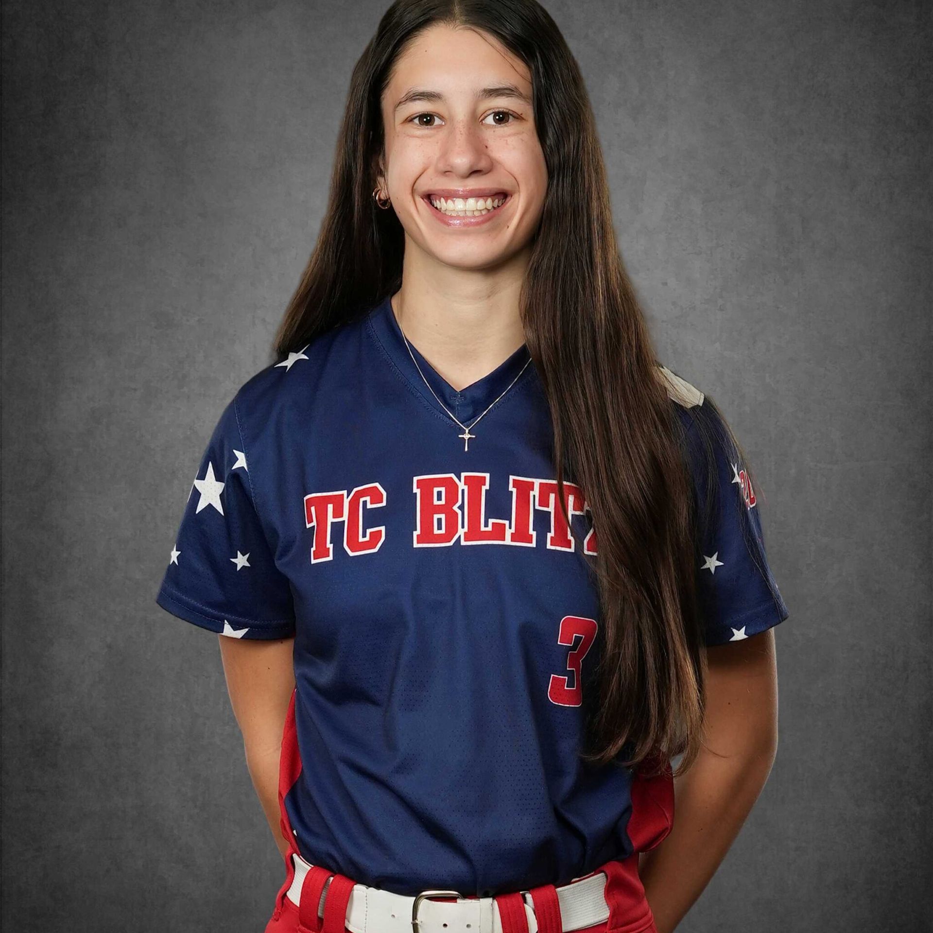 Smiling softball player in navy TC BLITZ jersey against a gray studio backdrop