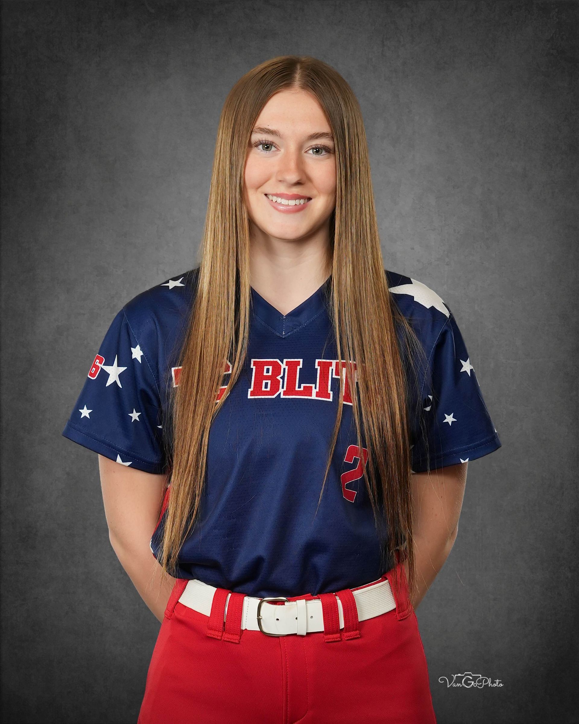 Portrait of a smiling athlete in a blue jersey and red pants against a gray studio backdrop