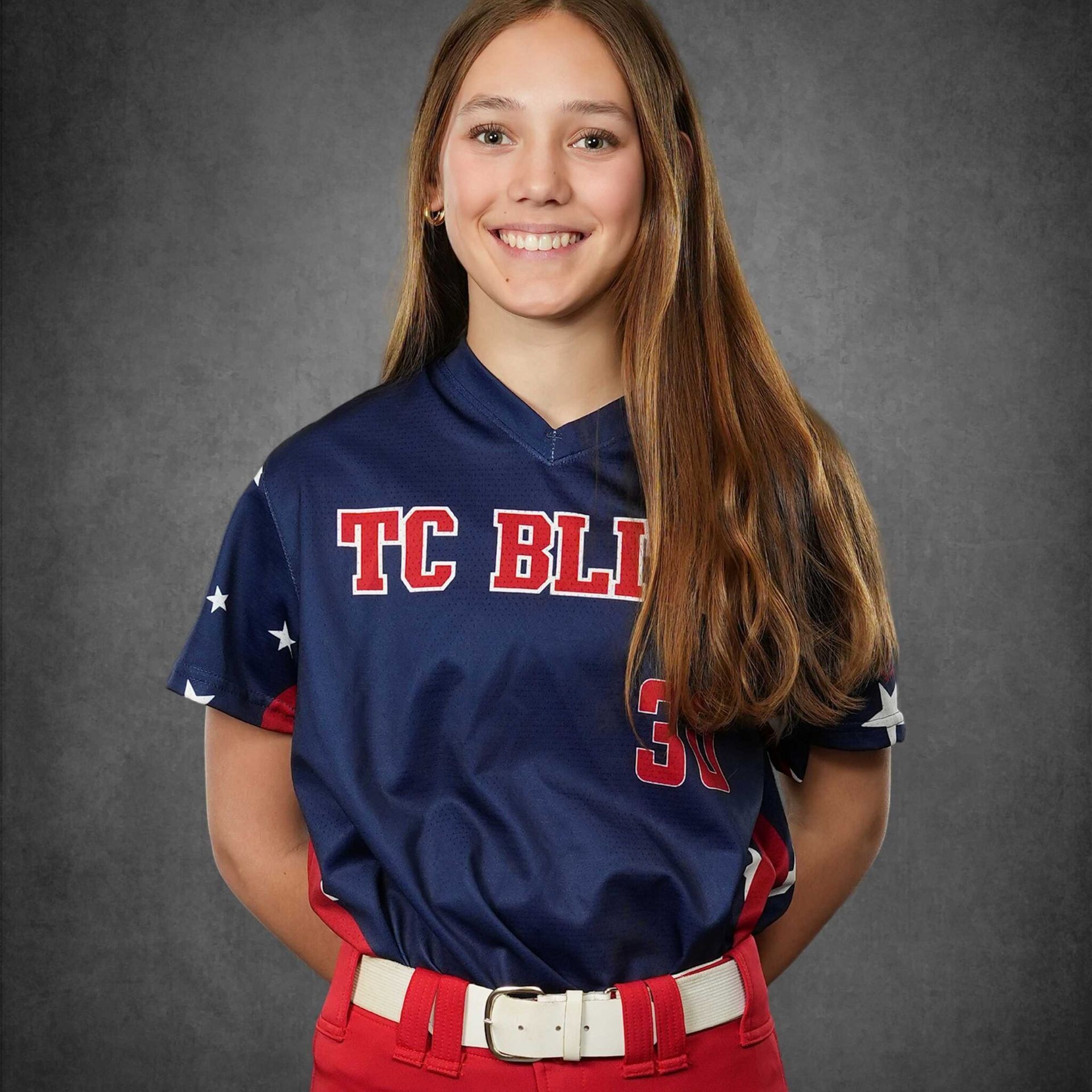 Smiling softball player in navy and red TC BL softball uniform against a gray backdrop