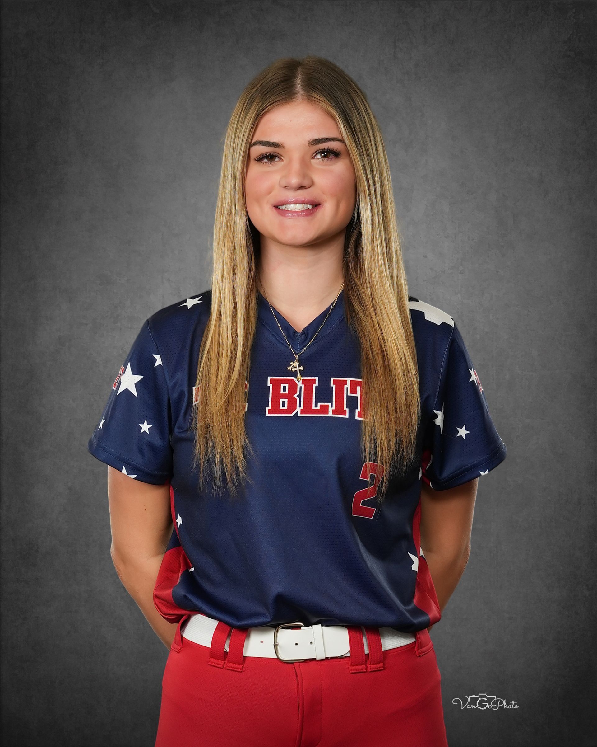 Portrait of a smiling athlete in a navy and red uniform against a gray studio backdrop