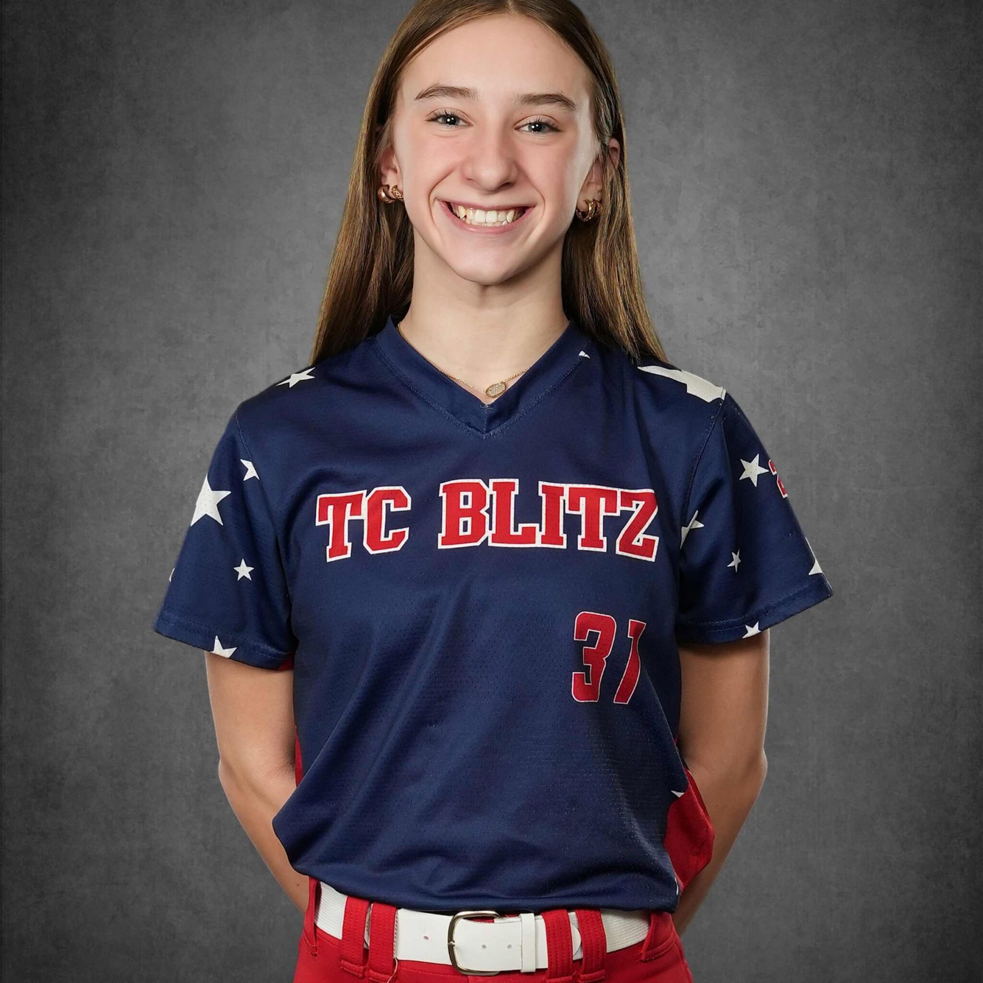 Smiling softball player in navy TC Blitz jersey posing against a gray backdrop