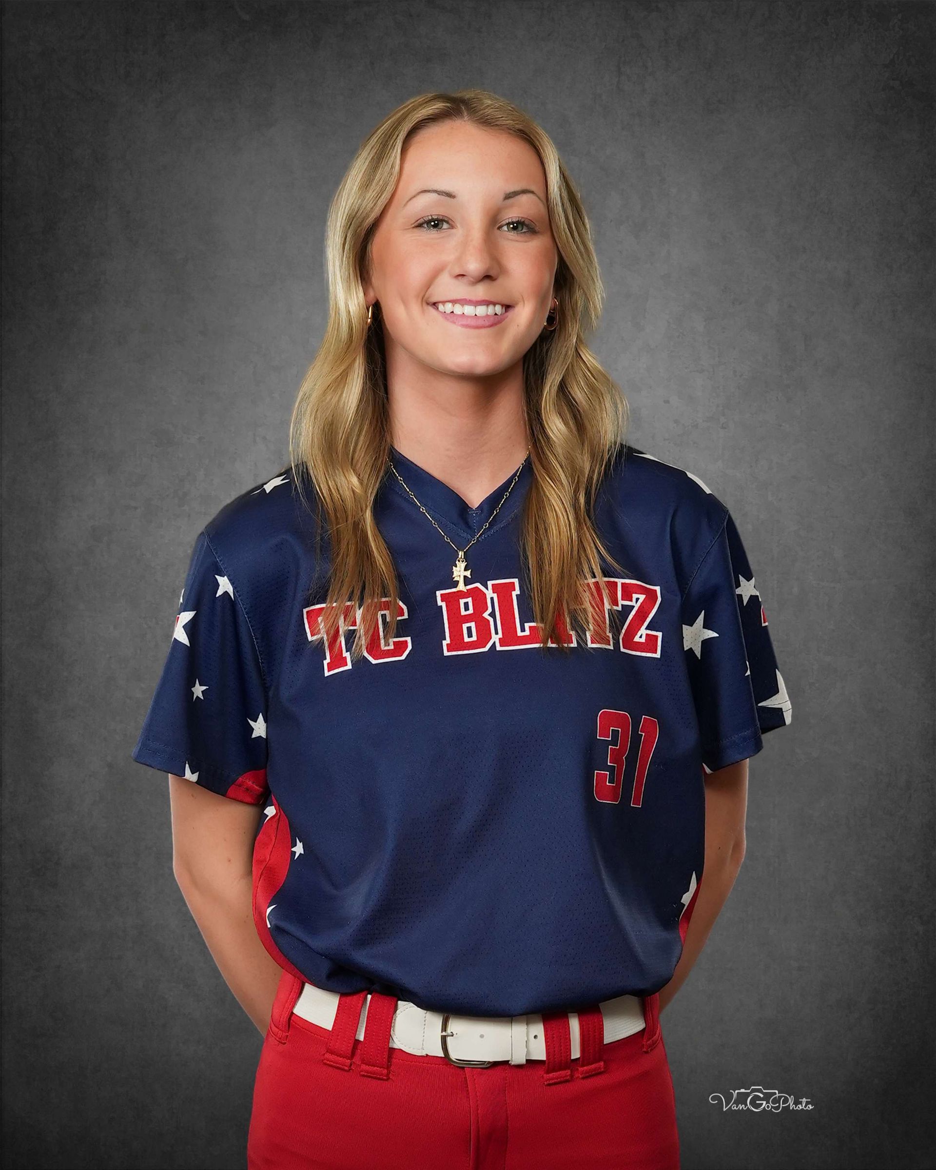 Woman in navy and red team uniform, smiling against a gray studio backdrop.